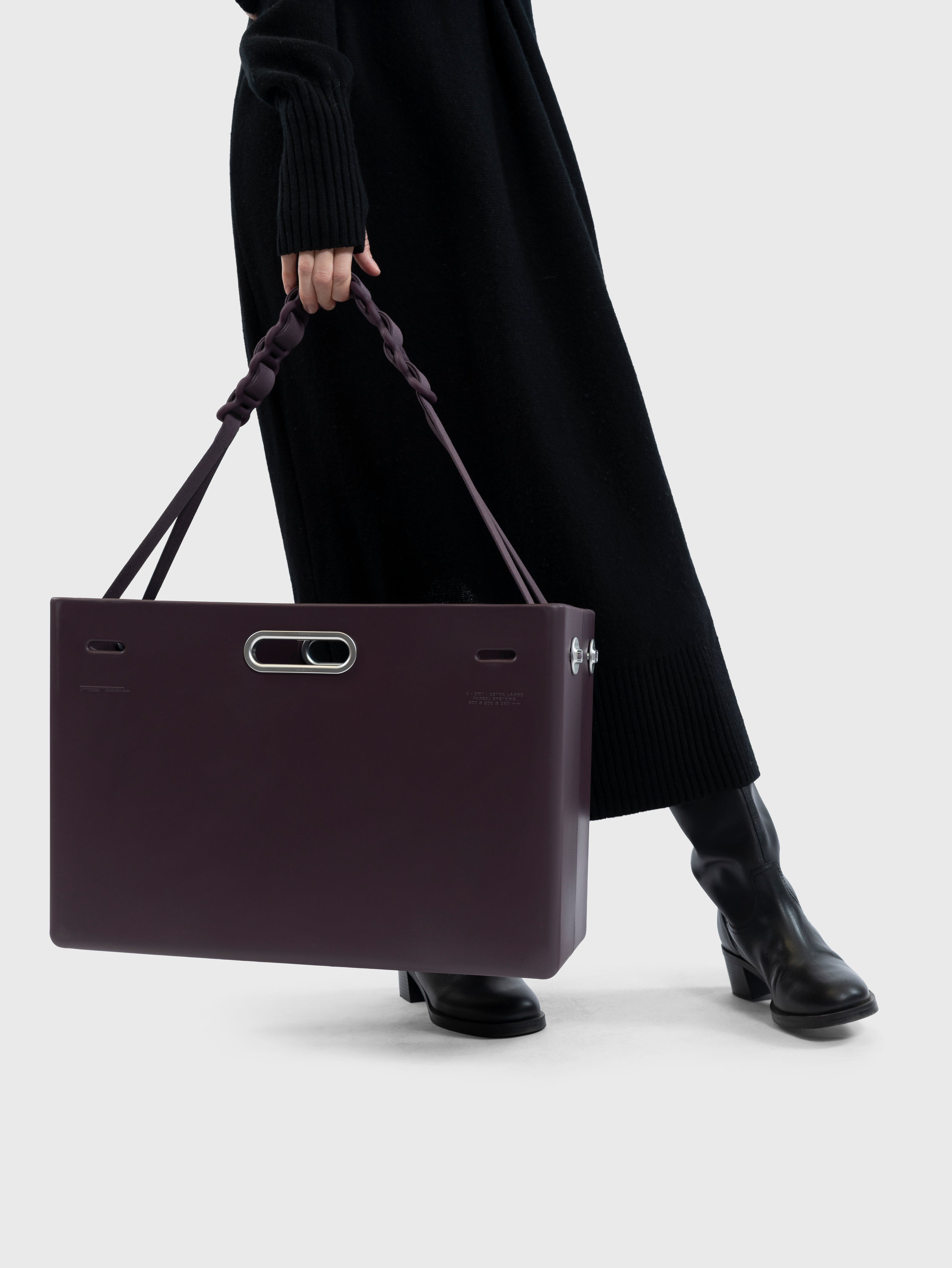 Person holding a dark purple PARSEL clutch bag against a white background